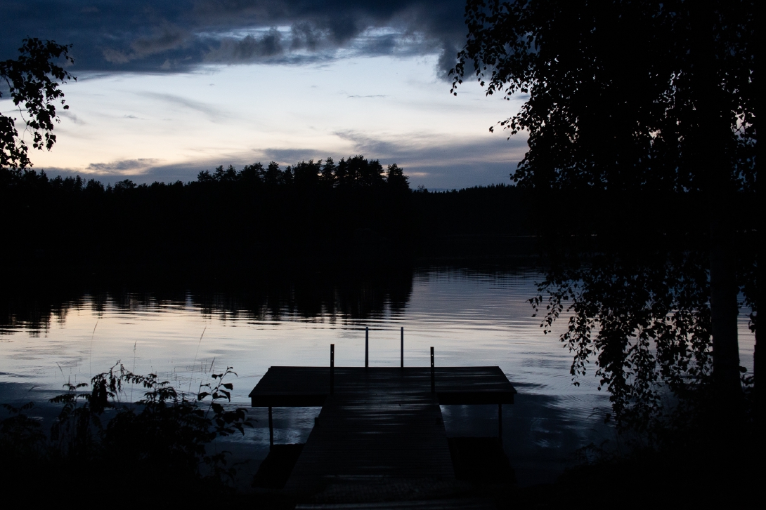 Kuva laiturista ja järvestä tummassa kesäyössä.